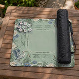 American mahjong mat with a sage-green pond scene, blue-grey herons, water lilies, reeds, and printed play-direction reminders around the edge.