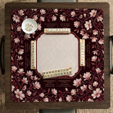 Cream American mahjong mat with a burgundy border of pale pink magnolia blossoms and printed play-direction and passing reminders.