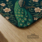 American mahjong mat with a deep teal-green background, peacocks, small cream flowers, leafy branches, and printed play-direction and Charleston reminders.