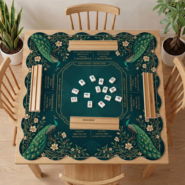 American mahjong mat with a deep teal-green background, peacocks, small cream flowers, leafy branches, and printed play-direction and Charleston reminders.