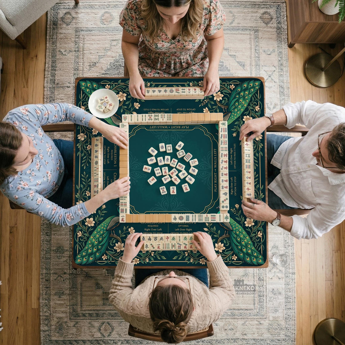 American mahjong mat with a deep teal-green background, peacocks, small cream flowers, leafy branches, and printed play-direction and Charleston reminders.
