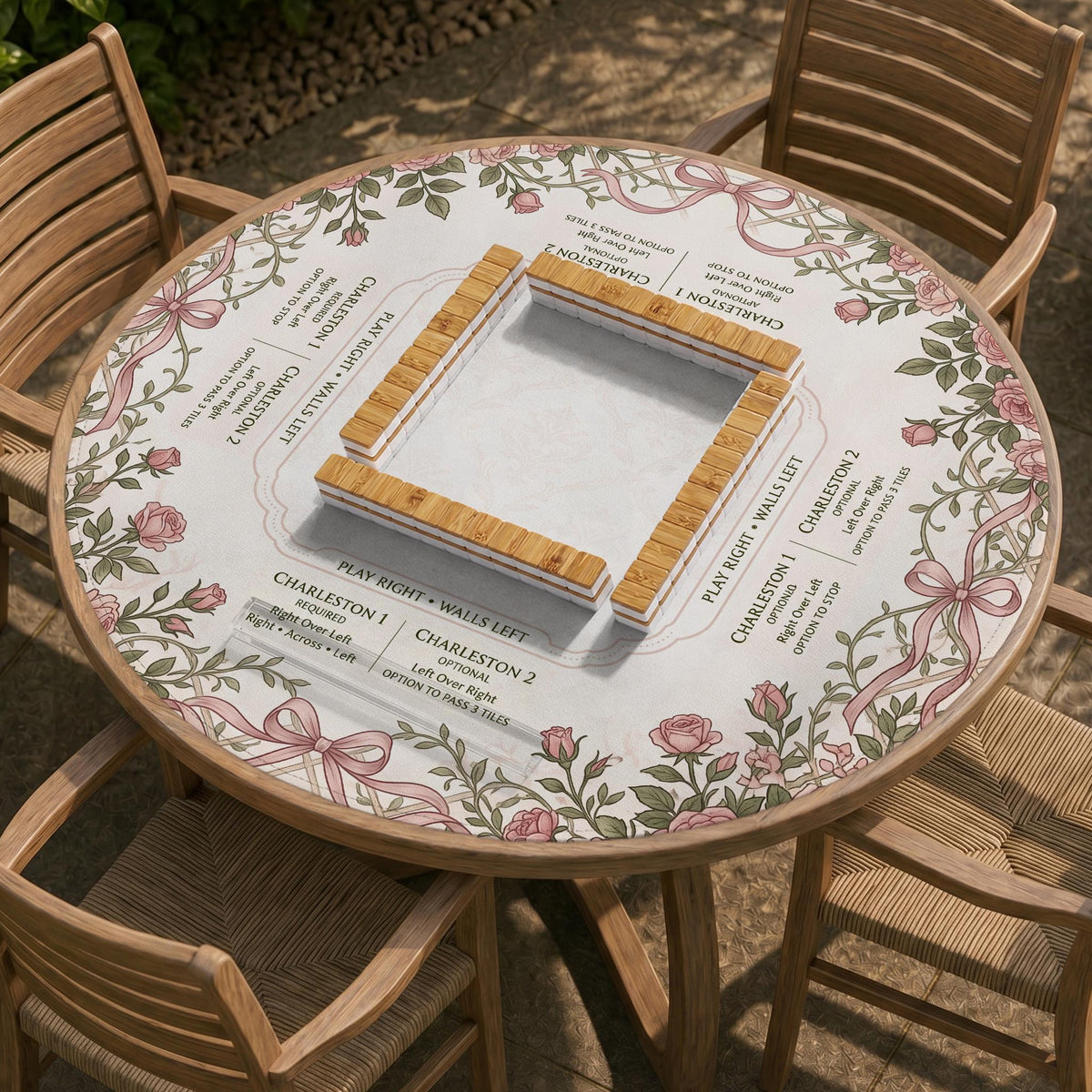 American mahjong mat with an ivory center, printed play-direction reminders, and a border of dusty-pink roses, ribbon bows, and green leaves.