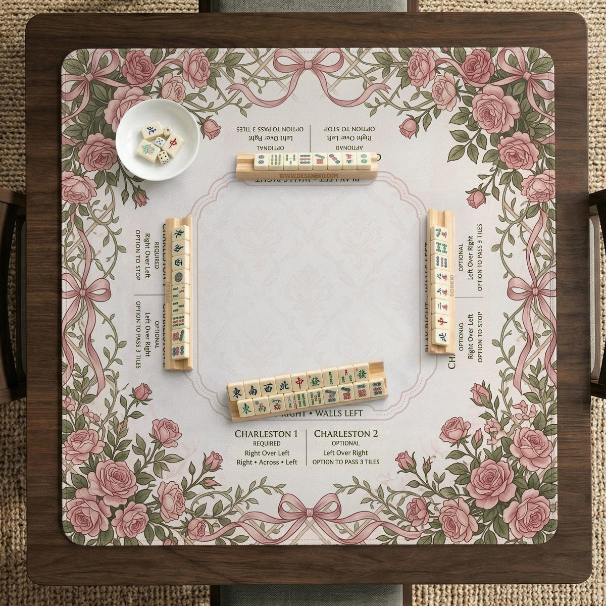 American mahjong mat with an ivory center, printed play-direction reminders, and a border of dusty-pink roses, ribbon bows, and green leaves.