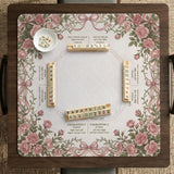 American mahjong mat with an ivory center, printed play-direction reminders, and a border of dusty-pink roses, ribbon bows, and green leaves.