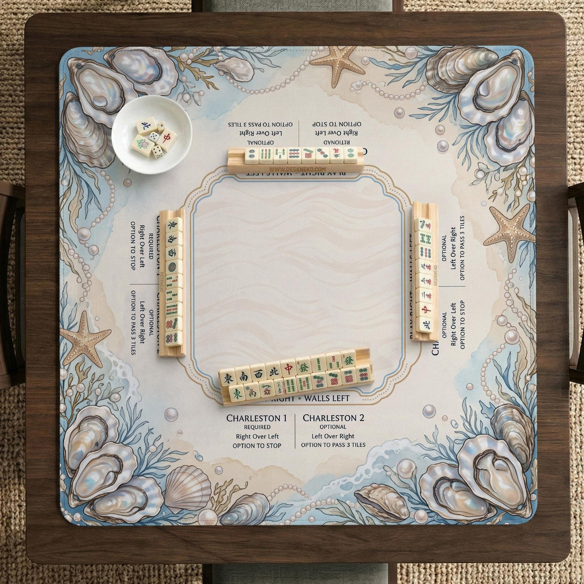 American mahjong mat with a cream center and a coastal border showing oyster shells, scallop shells, starfish, pearl strands, and pale blue sea plants.
