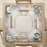 American mahjong mat with a cream center and a coastal border showing oyster shells, scallop shells, starfish, pearl strands, and pale blue sea plants.