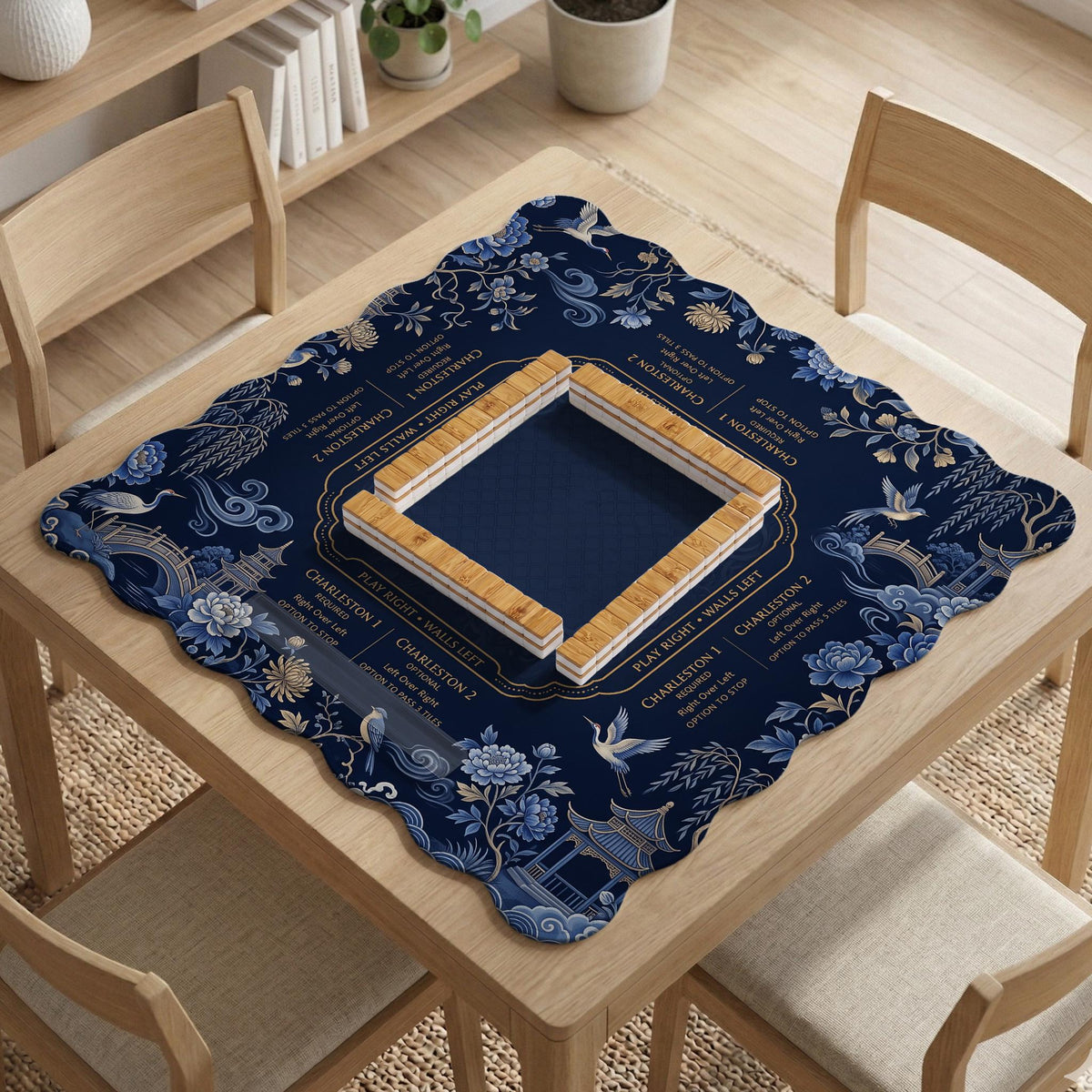 Navy mahjong mat with cranes, garden birds, pagodas, and blue and cream floral designs around a framed playing area with a printed Charleston guide.