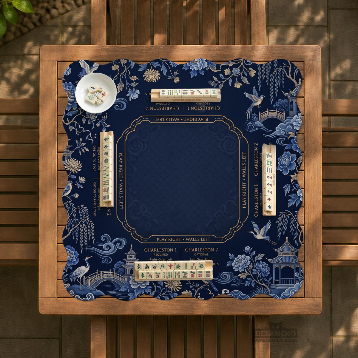 Navy mahjong mat with cranes, garden birds, pagodas, and blue and cream floral designs around a framed playing area with a printed Charleston guide.