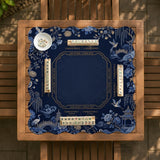 Navy mahjong mat with cranes, garden birds, pagodas, and blue and cream floral designs around a framed playing area with a printed Charleston guide.