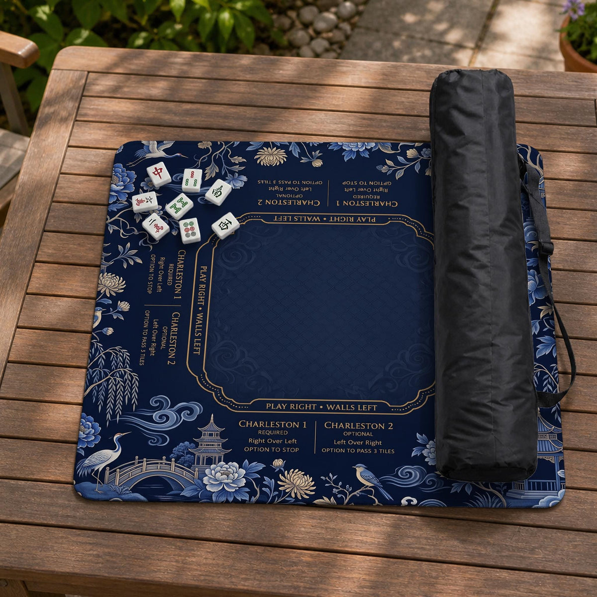 Navy mahjong mat with cranes, garden birds, pagodas, and blue and cream floral designs around a framed playing area with a printed Charleston guide.