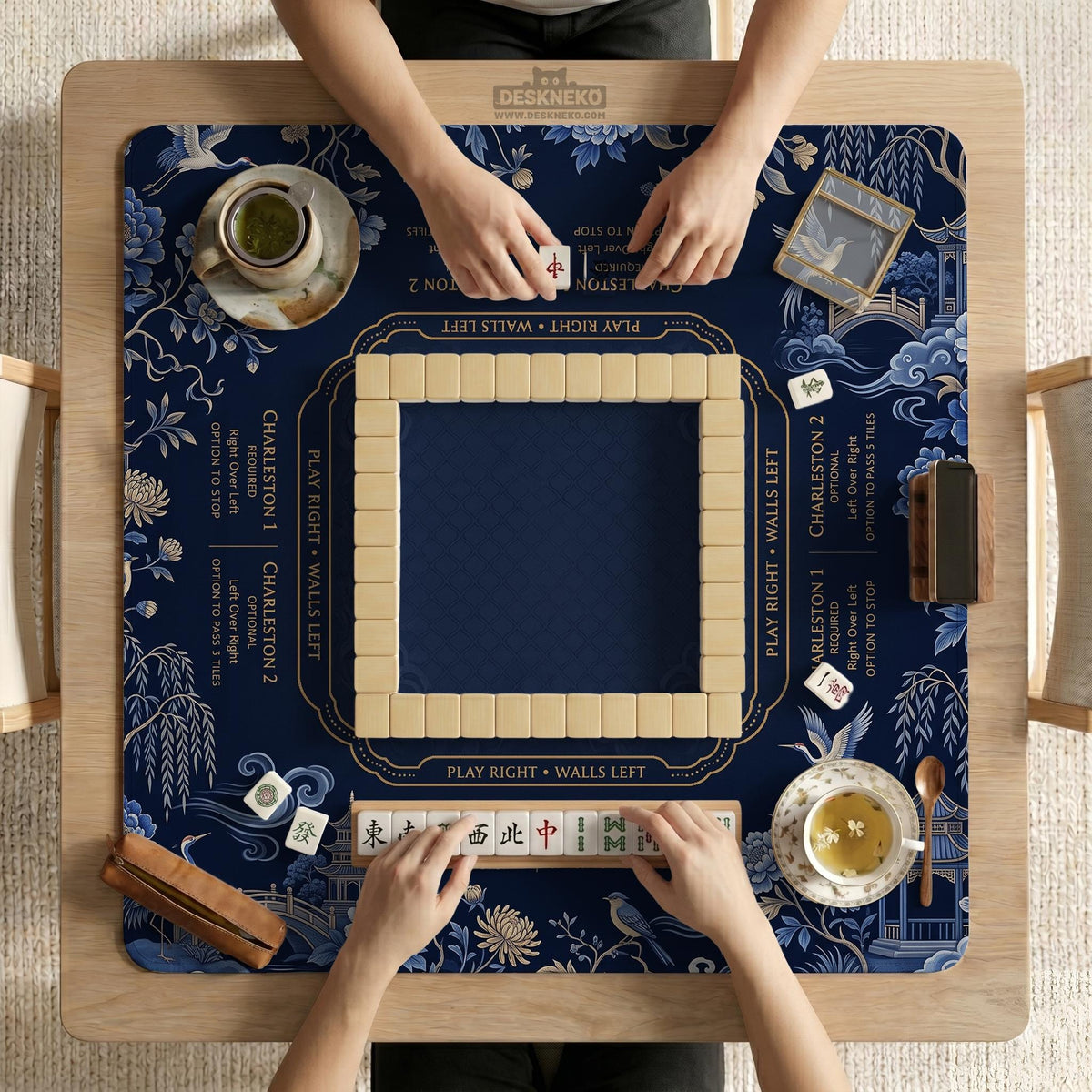 Navy mahjong mat with cranes, garden birds, pagodas, and blue and cream floral designs around a framed playing area with a printed Charleston guide.