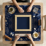Navy mahjong mat with cranes, garden birds, pagodas, and blue and cream floral designs around a framed playing area with a printed Charleston guide.