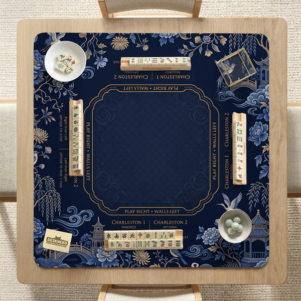 Navy mahjong mat with cranes, garden birds, pagodas, and blue and cream floral designs around a framed playing area with a printed Charleston guide.