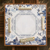 Square ivory mahjong mat with blue cranes, pagodas, flowers, and a blue border around the playing area.