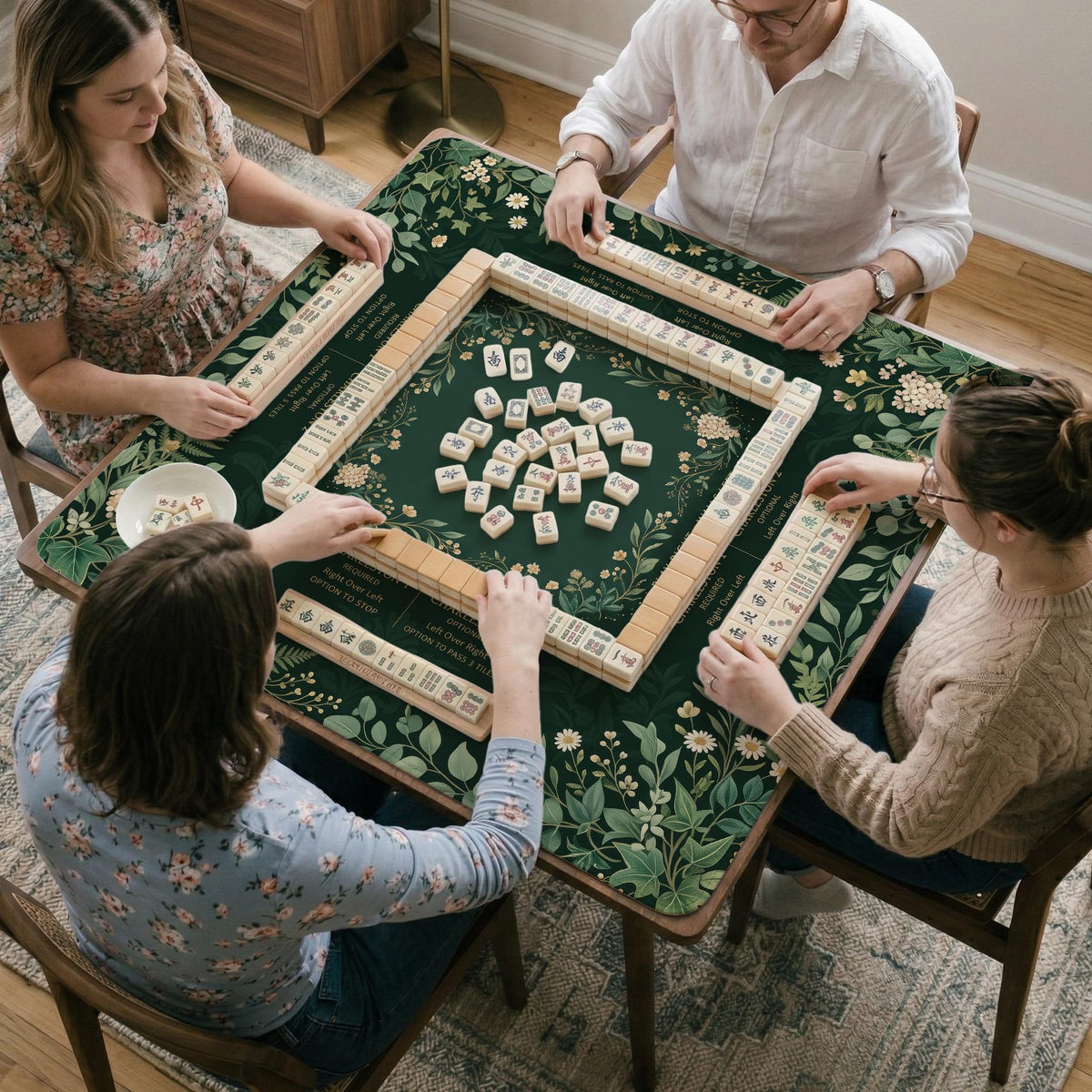 Square mahjong mat with a forest green botanical design, fern leaves, small cream flowers, and a printed Charleston guide around the center area.