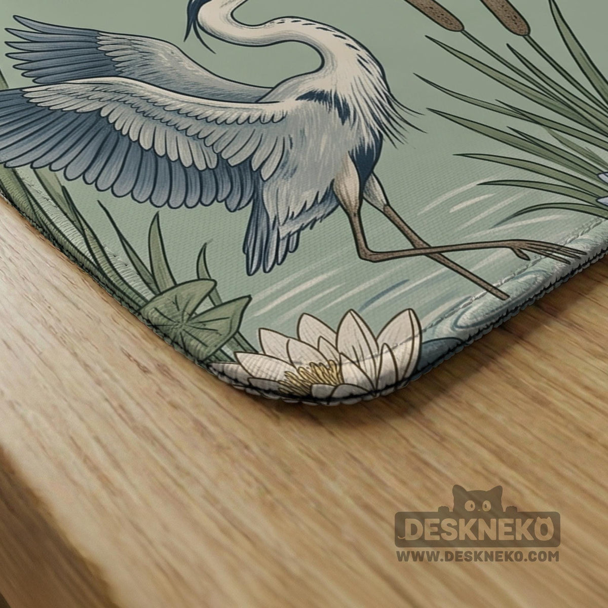 Square sage-green mahjong mat with blue-grey herons, water lilies, reeds, and printed play-direction and Charleston passing reminders around the playing area.