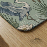 American mahjong mat with a sage-green pond scene, blue-grey herons, water lilies, reeds, and printed play-direction reminders around the edge.