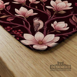 Cream American mahjong mat with a burgundy border of pale pink magnolia blossoms and printed play-direction and passing reminders.