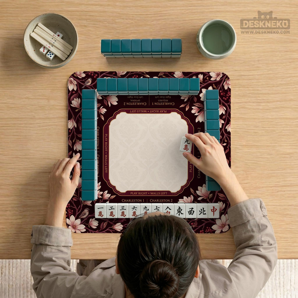 Cream American mahjong mat with a burgundy border of pale pink magnolia blossoms and printed play-direction and passing reminders.