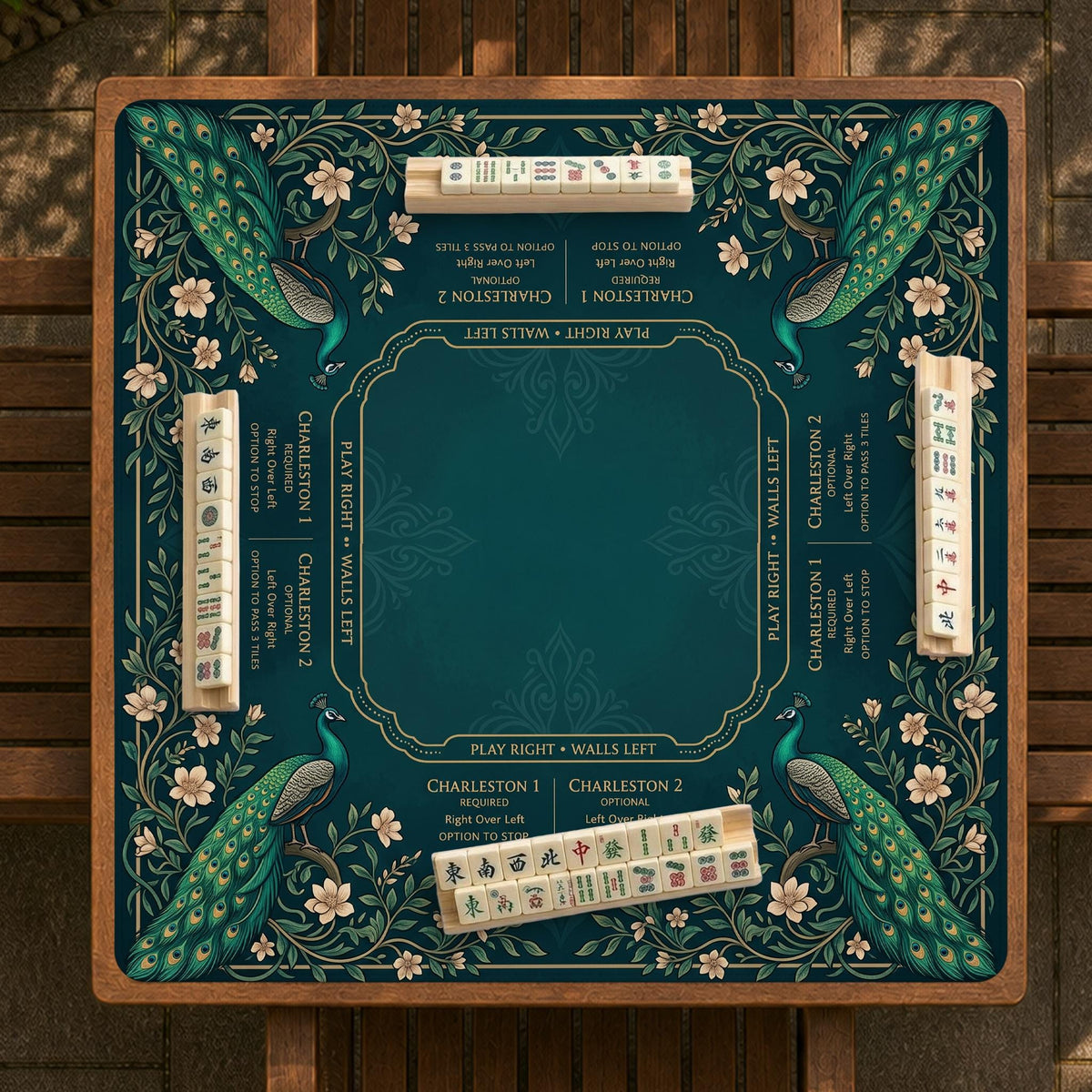 American mahjong mat with a deep teal-green background, peacocks, small cream flowers, leafy branches, and printed play-direction and Charleston reminders.