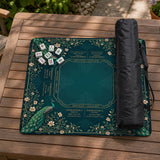 American mahjong mat with a deep teal-green background, peacocks, small cream flowers, leafy branches, and printed play-direction and Charleston reminders.
