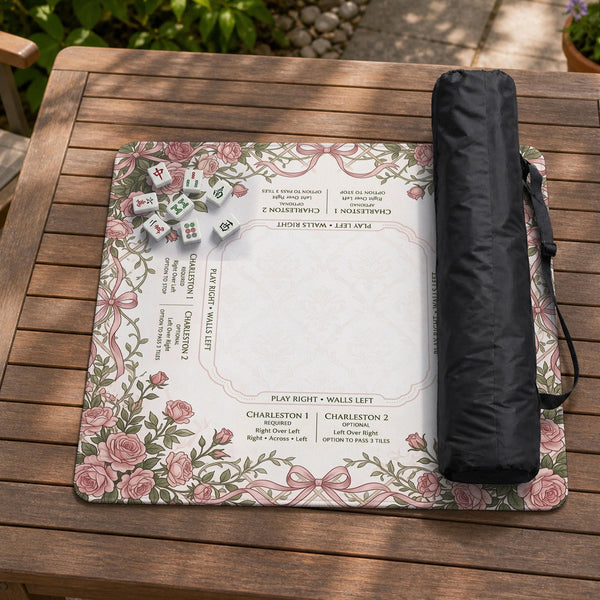 American mahjong mat with an ivory center, printed play-direction reminders, and a border of dusty-pink roses, ribbon bows, and green leaves.