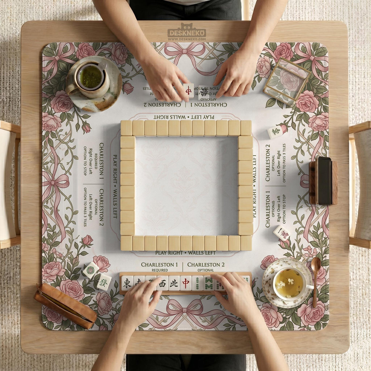 American mahjong mat with an ivory center, printed play-direction reminders, and a border of dusty-pink roses, ribbon bows, and green leaves.