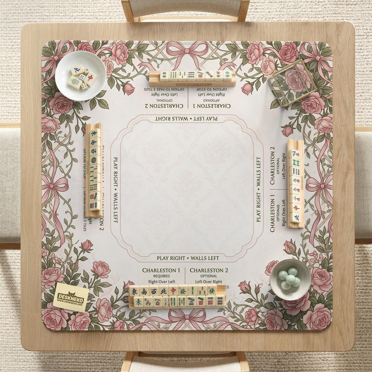 American mahjong mat with an ivory center, printed play-direction reminders, and a border of dusty-pink roses, ribbon bows, and green leaves.