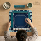 American mahjong mat with a navy-blue pond design, pale aqua lotus flowers, flowing water lines, koi fish, and printed play-direction and Charleston passing reminders.