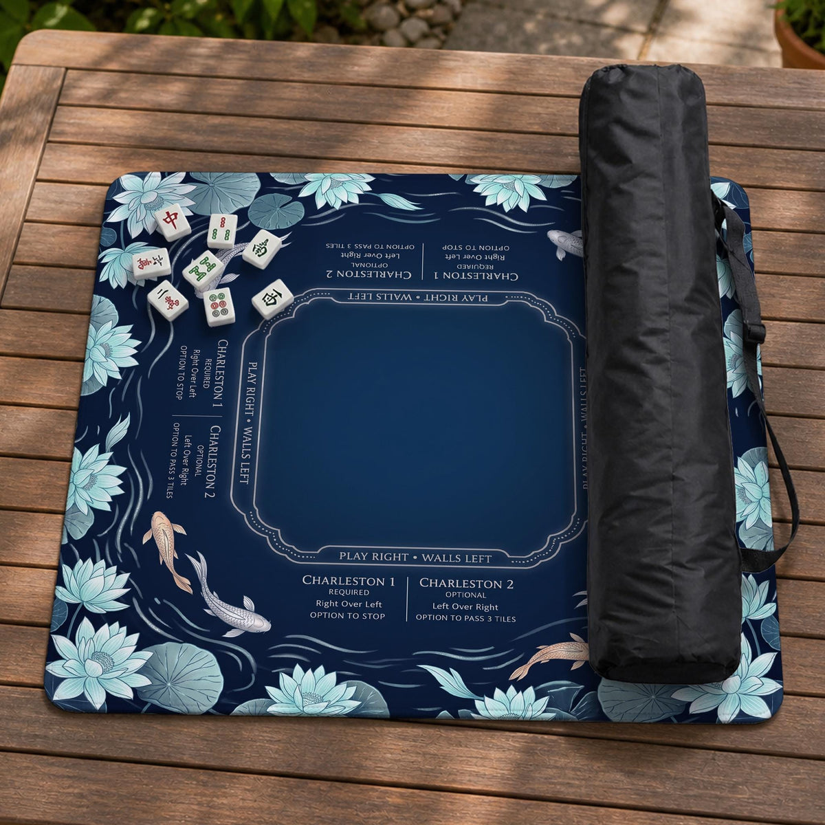 American mahjong mat with a navy-blue pond design, pale aqua lotus flowers, flowing water lines, koi fish, and printed play-direction and Charleston passing reminders.