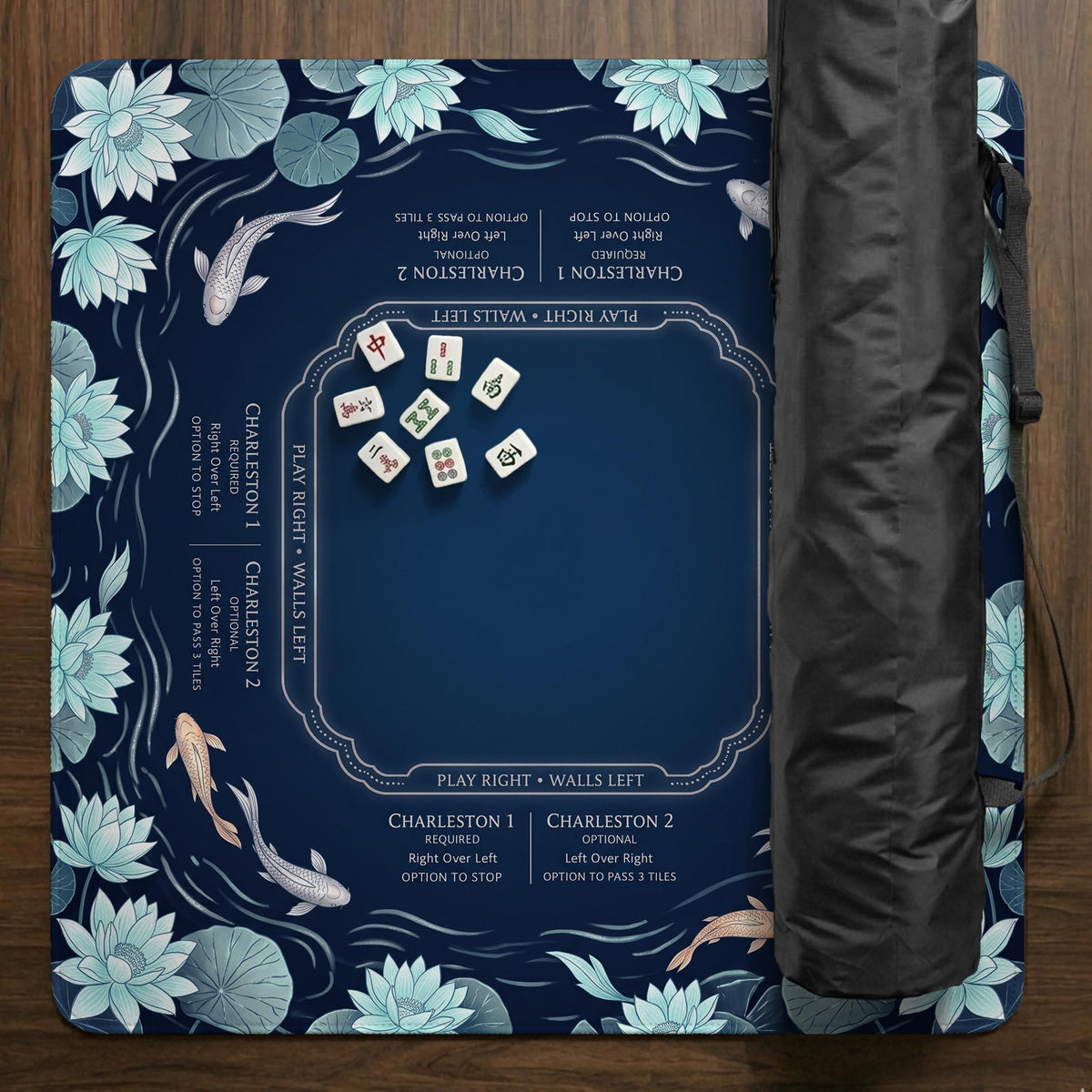 American mahjong mat with a navy-blue pond design, pale aqua lotus flowers, flowing water lines, koi fish, and printed play-direction and Charleston passing reminders.