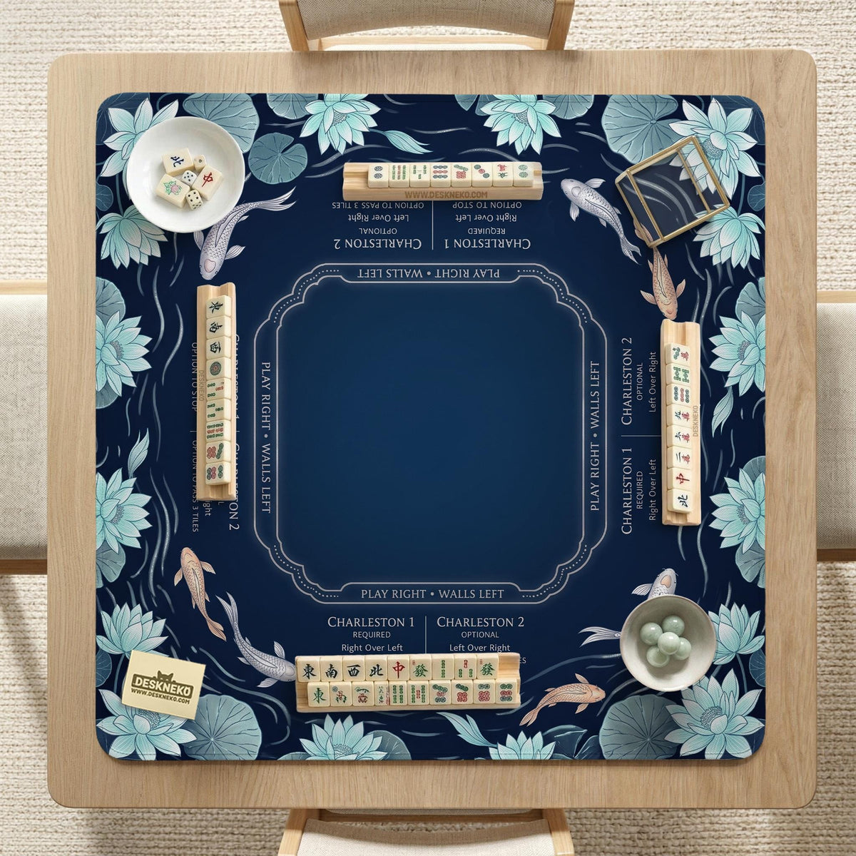 American mahjong mat with a navy-blue pond design, pale aqua lotus flowers, flowing water lines, koi fish, and printed play-direction and Charleston passing reminders.