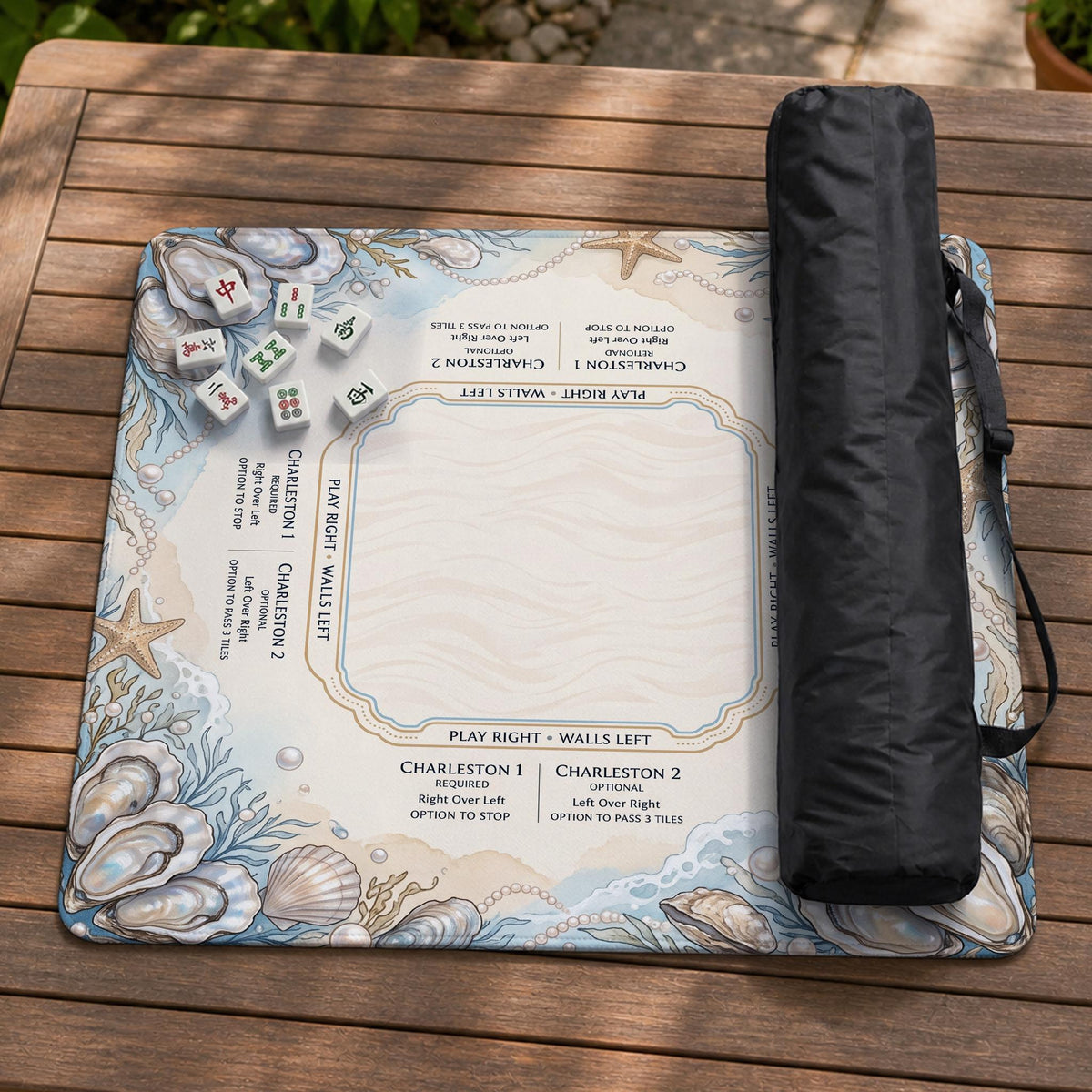 American mahjong mat with a cream center and a coastal border showing oyster shells, scallop shells, starfish, pearl strands, and pale blue sea plants.