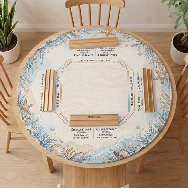 American mahjong mat with a cream center and a coastal border showing oyster shells, scallop shells, starfish, pearl strands, and pale blue sea plants.
