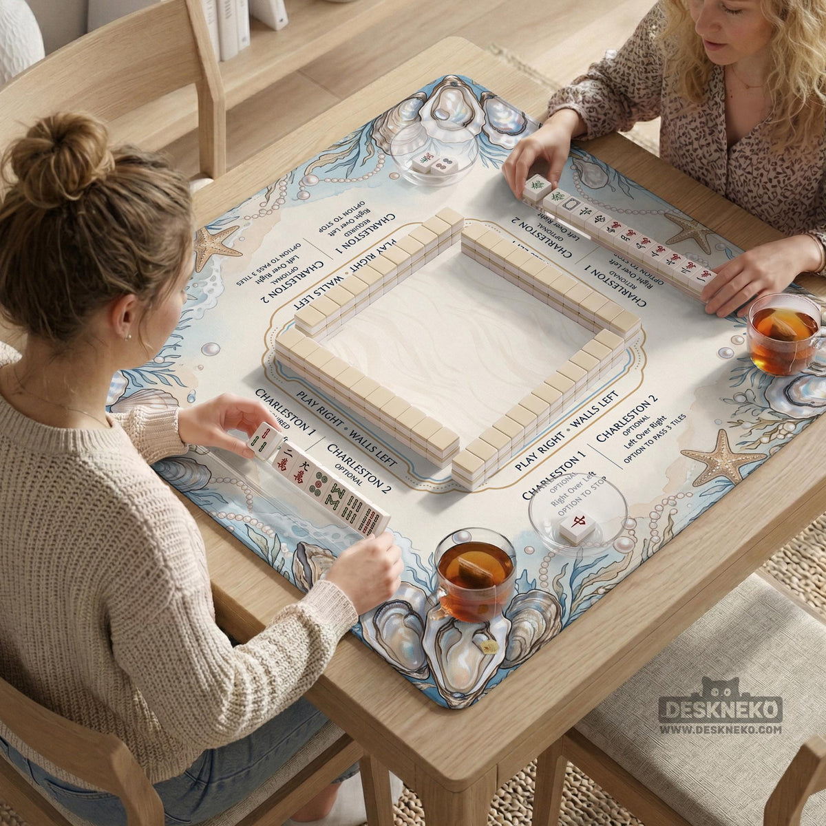 American mahjong mat with a cream center and a coastal border showing oyster shells, scallop shells, starfish, pearl strands, and pale blue sea plants.